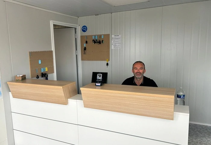 A man sitting at the front desk of a small office.